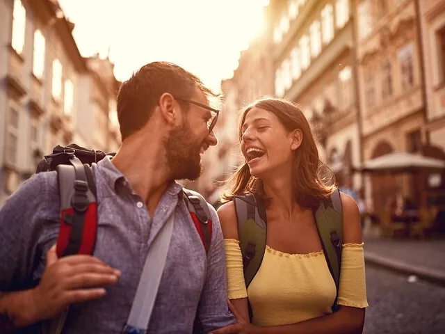A smiling couple walking together on a sunny European city street.
