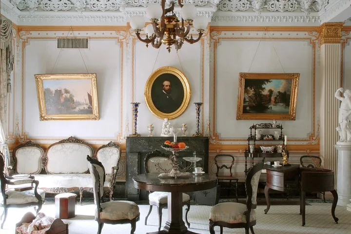 A formal sitting room featuring framed portraits and elegant antique furniture.