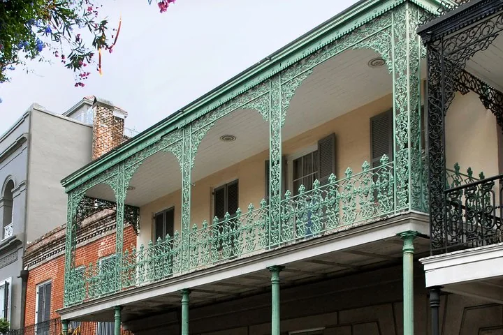 A detailed view of the long, elaborate cast-iron balcony of Gallier House.