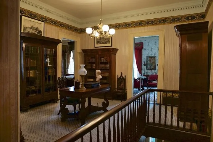 A well-appointed study or library with large wooden bookcases and a desk.