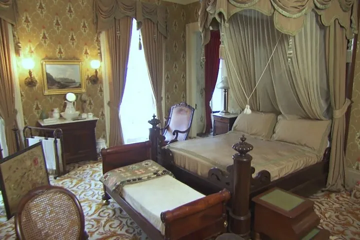Un gran dormitorio con una cama con dosel y cortinas pesadas.